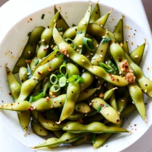 - 2 cups shelled edamame (fresh or frozen) - 3 tablespoons extra virgin olive oil - 4 cloves garlic, finely minced - 1 tablespoon red pepper flakes (or adjust to your spice preference) - 2 tablespoons low-sodium soy sauce - 1 tablespoon toasted sesame oil - 1 tablespoon freshly squeezed lemon juice - Sea salt, to taste These main ingredients create a bold and tasty dish. Edamame brings protein and a nice green color. Olive oil adds richness, while garlic gives depth and warmth. The red pepper flakes bring heat, so adjust them to your liking. Soy sauce adds umami, and sesame oil gives a nutty flavor. Lemon juice brightens everything up. - 2 green onions, thinly sliced (for garnish) - Toasted sesame seeds, for garnish Green onions add a sharp bite that contrasts well with the edamame. Sesame seeds provide a crunchy texture and nutty flavor. These garnishes make your dish look fancy and inviting. If you can't find edamame, you can swap in green peas. They offer a similar texture and taste. For olive oil, you can use canola oil or avocado oil. If you need a gluten-free option, use tamari instead of soy sauce. You can also adjust the spicy level by using less red pepper flakes or adding fresh chili for more heat. {{ingredient_image_2}} Start with shelled edamame. If you use frozen, boil them. Follow the package instructions. Usually, it takes about 4 to 5 minutes. They should be tender and bright green. Drain the edamame well and set them aside. This step is simple, but it sets the stage for flavor. Next, heat 3 tablespoons of extra virgin olive oil in a large skillet. Keep the heat at medium until the oil shimmers. Add 4 cloves of finely minced garlic. Saut&eacute; for about 1 minute. You want the garlic to smell great and turn golden. Be careful not to burn it. Then, add 1 tablespoon of red pepper flakes. Stir for another 30 seconds to enhance the flavor. Now, add the cooked edamame to the skillet. Pour in 2 tablespoons of low-sodium soy sauce and 1 tablespoon of toasted sesame oil. Toss everything together quickly. Make sure the edamame is well-coated in the spicy garlic mix. Drizzle 1 tablespoon of freshly squeezed lemon juice on top. Stir well and taste. Adjust sea salt if needed. Finally, transfer your dish to a serving plate. Garnish with thinly sliced green onions and toasted sesame seeds. Enjoy your colorful and tasty creation! To adjust the spice, you can change the red pepper flakes. Start with one teaspoon for a mild kick. If you love heat, add more flakes until you reach your desired level. You can also add a dash of hot sauce for extra flavor. Want more flavor? Try adding a splash of rice vinegar. It adds a nice tang. You can also mix in a teaspoon of honey for sweetness. This balance of flavors makes the dish pop. Fresh herbs like cilantro or basil can brighten the taste too. Serve your Spicy Garlic Edamame in a bright bowl. This makes the dish stand out. Use toothpicks for easy snacking. To show off your dish, sprinkle extra sesame seeds on top. A small bowl of chili oil on the side adds a fun touch and lets guests add more heat. Pro Tips Fresh Ingredients: Use fresh edamame whenever possible for the best flavor and texture. Frozen edamame is a good alternative if fresh is not available, but be sure to cook them properly. Adjusting Spice Levels: Feel free to adjust the amount of red pepper flakes based on your heat tolerance. Start with a small amount and gradually add more to find your perfect spice level. Perfectly Saut&eacute;ed Garlic: Keep an eye on the garlic while saut&eacute;ing; it can burn quickly. Remove it from heat as soon as it turns golden to avoid a bitter taste. Garnishing for Flavor: Don&rsquo;t skip the garnishes! Green onions and toasted sesame seeds add not only a visual appeal but also a delightful crunch and extra flavor to the dish. {{image_4}} You can change the flavor of your spicy garlic edamame easily. Try adding lime juice instead of lemon. This will give a bright, zesty twist. For a sweet touch, mix in a teaspoon of honey or maple syrup. You could also use different oils, like chili oil, for a richer flavor. Experiment with herbs too! Fresh cilantro or parsley can add a nice touch. Want to make this dish heartier? Add protein like shrimp or chicken. Cook them in the skillet before adding garlic and edamame. Tofu is a great option for a plant-based boost. Simply cube it and saut&eacute; until golden. You can even sprinkle cooked bacon pieces on top for a smoky flavor. These additions will make your dish filling and tasty. This recipe is already vegan and can be gluten-free! Use tamari instead of soy sauce for a gluten-free option. Always check labels when buying sauces. For a nutty twist, add a splash of almond or peanut sauce. You can also include fresh veggies like bell peppers or snap peas to enhance nutrition. Enjoy your spicy garlic edamame with these simple tweaks! To keep your Spicy Garlic Edamame fresh, store leftovers in an airtight container. Make sure the dish cools to room temperature first. Place it in the fridge and enjoy it within three days for the best flavor. To reheat, you can use the microwave or stovetop. If using the microwave, heat for about 1-2 minutes. Stir halfway through to warm evenly. If you choose the stovetop, add a splash of water in a skillet and heat over low heat. Stir often until hot. You can freeze Spicy Garlic Edamame for later use. First, let it cool completely. Then, place it in a freezer-safe bag or container. Remove as much air as possible. It will stay fresh for up to three months. When ready to eat, thaw in the fridge overnight and reheat. Cooking frozen edamame takes about 4 to 5 minutes. Boil them in salted water until they are tender. Once cooked, drain the edamame well. This quick cook time keeps the beans bright and tasty. Yes, you can prepare Spicy Garlic Edamame ahead of time. Cook the edamame and mix in the garlic sauce. Store it in the fridge for up to two days. Reheat it in a skillet before serving. The flavors will blend nicely as it sits. Spicy Garlic Edamame pairs well with various dishes. Try serving it with sushi, rice bowls, or grilled meats. It also makes a great snack when served with cocktails or beer. Add some chili oil on the side for extra spice. Spicy Garlic Edamame is simple and delicious. You learned about key ingredients, cooking steps, and helpful tips. I showed you how to adjust flavors and even try new variations. Storing and reheating tips ensure you enjoy leftovers too. Remember, cooking is fun, so don&rsquo;t be afraid to experiment. Each bite should bring joy and excitement. Enjoy your cooking journey with this tasty dish!