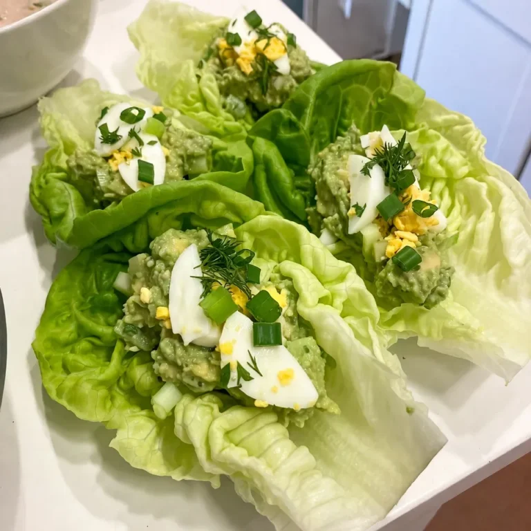 To make delicious avocado egg salad lettuce wraps, you need simple and fresh ingredients. Here’s what you’ll need: - 4 hard-boiled eggs, peeled and roughly chopped - 1 ripe avocado, mashed until creamy - 2 tablespoons Greek yogurt (or mayonnaise for a richer flavor) - 1 tablespoon Dijon mustard for a tangy kick - 1 tablespoon freshly squeezed lemon juice - 2 green onions, finely chopped - 1 small celery stalk, diced very small for crunch - Salt and freshly cracked pepper to taste - 8 large lettuce leaves (preferably romaine or butter lettuce for flexibility) - Optional: Fresh herbs like dill or parsley, finely chopped, for garnish Each ingredient plays a key role. The hard-boiled eggs give protein and heartiness. The ripe avocado adds creaminess and healthy fats. Greek yogurt or mayonnaise gives the salad a nice richness. Dijon mustard and lemon juice add zing and brightness. Green onions and celery boost the freshness and crunch. Using large lettuce leaves makes these wraps easy to hold. Optional herbs add a pop of flavor and color. Choose fresh, vibrant produce for the best taste. {{ingredient_image_2}} - Chopping Hard-Boiled Eggs Start with four hard-boiled eggs. Peel them. Chop the eggs roughly with a knife. You want some chunks for texture. - Mashing the Avocado Next, grab one ripe avocado. Cut it in half. Remove the pit and scoop the flesh into a bowl. Mash it with a fork until creamy. - Dicing Celery and Green Onions Now, take one small celery stalk. Dice it very small for a nice crunch. Then, finely chop two green onions. These will add flavor and freshness. - Combining Ingredients in a Bowl In a large mixing bowl, add the chopped eggs and mashed avocado. Stir gently with a fork to mix. - Adjusting Seasonings Add two tablespoons of Greek yogurt or mayonnaise, one tablespoon of Dijon mustard, and one tablespoon of lemon juice. Mix well. Taste your salad and add salt and pepper to your liking. - Spoon Filling into Lettuce Leaves Take a large lettuce leaf, like romaine or butter lettuce. Spoon a generous amount of the avocado egg salad into the center of the leaf. - Folding Technique for Wraps Fold the sides of the lettuce leaf over the filling. Then, roll it up gently. This makes a tasty wrap that holds together well. - Achieving the Right Creaminess To get the best creaminess, mash the avocado well. It should be smooth but not completely blended. This adds body and richness to the egg salad. Mix in Greek yogurt or mayonnaise to enhance the texture. Each adds a unique flavor that makes the salad irresistible. - Balancing Flavors Balancing flavors is key. The tang from Dijon mustard and lemon juice brightens the dish. Adjust these ingredients to your taste. Add salt and freshly cracked pepper slowly. Taste as you go. This ensures your egg salad shines with every bite. - Plating and Presentation Ideas Serve these wraps on a colorful platter. Place the wraps neatly and add a bowl of leftover filling for guests. It invites everyone to dig in. Garnish with fresh herbs and halved cherry tomatoes. This makes the dish look fresh and inviting. - Pairing with Sides or Dips Pair your wraps with crunchy veggie sticks or a light dip. Hummus or tzatziki works well. These sides complement the flavors of the egg salad and add variety to your meal. - Ingredient Swaps and Additions Feel free to swap ingredients to suit your taste. If you like spice, add some chopped jalapeños. Want more crunch? Toss in diced bell peppers or pickles. These changes can make your wraps even more enjoyable. - Dietary Considerations For vegan options, replace eggs with mashed chickpeas. Use plant-based yogurt to keep it creamy. This keeps the wrap tasty and healthy for everyone. Always consider dietary needs to ensure everyone can enjoy your creation. Pro Tips Choose Ripe Avocados: Make sure your avocados are perfectly ripe for the creamiest texture. They should yield slightly to gentle pressure when squeezed. Hard-Boil Eggs Perfectly: For easy peeling, use eggs that are at least a week old. Boil them gently and then plunge them into an ice bath immediately after cooking. Customize Your Dressing: Feel free to experiment with different herbs and spices. Adding a pinch of paprika or cayenne pepper can give your salad an exciting twist! Keep It Fresh: To prevent the avocado from browning, you can add extra lemon juice to the salad mixture or cover it tightly with plastic wrap until serving. {{image_4}} For your avocado egg salad, you can choose different types of lettuce. Romaine lettuce is crisp and sturdy, making it great for wraps. It holds the filling well without tearing. Butter lettuce is softer and has a sweet taste. It adds a different texture. Both options work well, so pick what you like best. You can also use other greens. Try collard greens for a hearty alternative. They are thick and can hold the filling well. Spinach leaves are another great choice. They are tender and add a fresh flavor. Experiment with what you have on hand! You can enhance the flavor of your egg salad by adding spices or seasonings. A pinch of paprika gives a nice kick. You might also add cayenne pepper for some heat. If you like garlic, mix in a little garlic powder or fresh minced garlic. Think about mix-ins for extra flavor. Chopped pickles bring a tangy crunch. You can also add diced bell peppers or even sun-dried tomatoes. Each choice brings a new twist to your salad! If you want vegan alternatives, replace the eggs with mashed chickpeas. You can still use avocado for creaminess. Instead of Greek yogurt, try using vegan mayo. It keeps the salad smooth and tasty. For low-carb modifications, skip the yogurt and use more avocado. You can also reduce the amount of mustard. Just be mindful of the flavors as you adjust. This way, you can enjoy a healthy, delicious wrap! - Refrigeration Tips: Place your avocado egg salad in the fridge right away. This keeps it fresh. Make sure it cools down before sealing. - Best Containers for Storage: Use airtight containers to store your salad. Glass or plastic works well. These keep air out and prevent spoilage. - How Long It Lasts in the Fridge: Your egg salad lasts about 3 to 5 days if stored properly. Always check the date you made it. - Signs of Spoilage: Look for changes in color or smell. If it smells bad or the texture feels off, throw it away. - Can You Reheat Egg Salad?: It's best not to reheat egg salad. The texture and taste can change. Enjoy it cold for the best flavor. - Best Practices for Serving: Serve your salad fresh in lettuce wraps. If it has been in the fridge, give it a quick stir before serving. This helps mix the flavors again. Yes, you can prepare avocado egg salad ahead of time. To keep it fresh, store it in an airtight container. Add lemon juice to slow browning from the avocado. This dish tastes great chilled. Mix the ingredients and let them sit for a few hours. This helps flavors blend. Remember to eat it within two days for the best taste. Choose ripe avocados for this recipe. A ripe avocado feels slightly soft when you press it gently. The skin should be dark green or nearly black. Avoid avocados with large dark spots or a mushy feel. These may be overripe. The creamy texture of ripe avocados enhances the egg salad. This makes your dish smooth and flavorful. Yes, you can use regular mustard instead of Dijon. Yellow mustard adds a milder flavor. If you want a bit of heat, try spicy brown mustard. Each mustard type brings its own taste. Experiment with what you like best. The key is to find a mustard that suits your palate. Adjust the amount based on your taste preference. In this post, we explored how to make tasty avocado egg salad lettuce wraps. We covered the key ingredients, like hard-boiled eggs and ripe avocado, and detailed step-by-step instructions for preparation. I shared tips for perfecting your egg salad and variations to keep it exciting. Remember to store leftovers properly for the best taste. With these ideas, you can enjoy a healthy, tasty meal that fits your needs. Enjoy creating your own wraps!